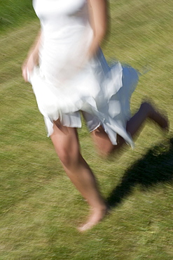 Young woman runs in a white dress without shoes over a meadow