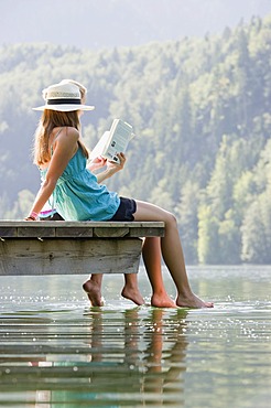 Young women sitting on a landing stage on Lake Schwansee near Fuessen, Allgaeu region, Bavaria, Germany, Europe