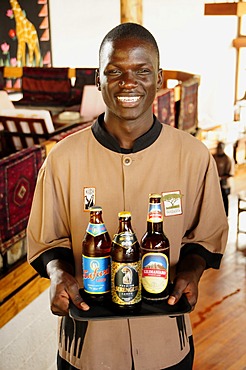 Waiter carrying the three most popular beers in Tanzania, Serengeti, Kilimanjaro and Safari, Lobo Wildlife Lodge, Serengeti National Park, Tanzania, Africa