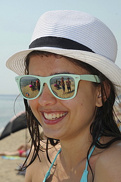 Smiling girl on the beach, wearing sunglasses