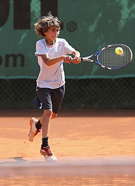 Boy, 10, playing tennis, hitting with a two-handed backhand, Munich, Upper Bavaria, Bavaria, Germany