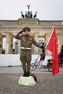 A man dressed up as a soviet army soldier poses in front of the Brandenburger Tor, Berlin