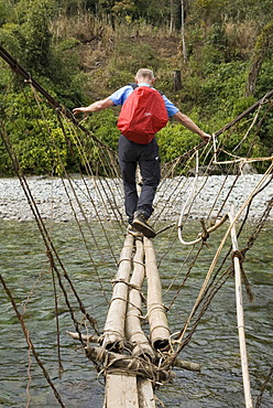 Man crossing a narrow suspension bridge, Kachin State, Myanmar