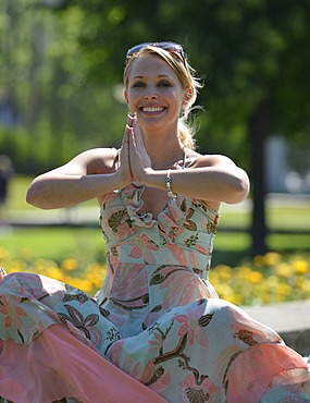 Young woman wearing a summer dress sitting in a yoga position, Schlosspark garden, Stuttgart, Baden-Wuerttemberg, Germany, Europe, PublicGround