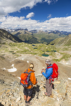 Two hikers on the Fuorcia da Barcli pass, overlooking the Macun Lakes, Swiss National Park, GraubÃ¼nden, Switzerland, Europe