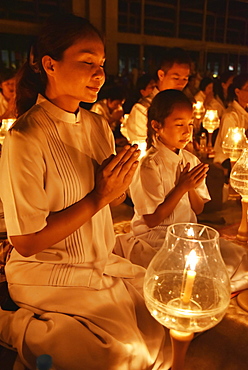 Young woman and child praying, candlelight, Wat Phra Dhammakaya temple, Bangkok, Thailand, Asia