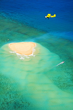 Small plane flying over coral reef with sand island, near Grande Terre island, Mayotte, Africa