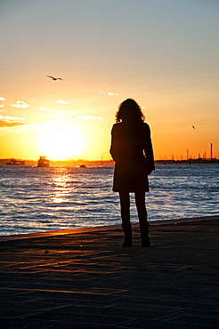 Woman watching the sunset on the Zattere promenade, Venice, Italy, Europe