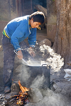 Boy preparing breakfast, open fire, boarding school, Potosi, Bolivia, South America