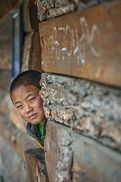 A boy looks out of a house, Wangue, Himalayas, Kingdom of Bhutan