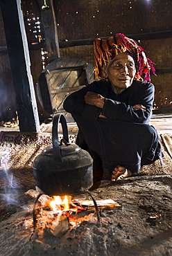 Old woman in the kitchen, kettle on an open fire place in the lodge, mountain tribe or mountain people Pa-O or Pa-Oh or Pao or Black Karen or Taungthu or dew-soo, ethnic minority, near Kalaw, Shan State, Myanmar, Asia