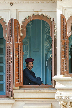 Museum guard sitting by the window in the City Palace of the Maharaja, Udaipur, Rajasthan, India, Asia