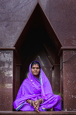 Elderly woman sitting in front of a temple in Pushkar, Rajasthan, India, Asia