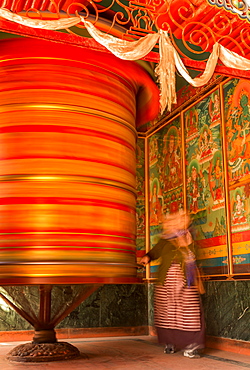 A female devotee spinning a large prayer wheel, Boudhanath, Kathmandu, Kathmandu District, Bagmati Zone, Nepal, Asia