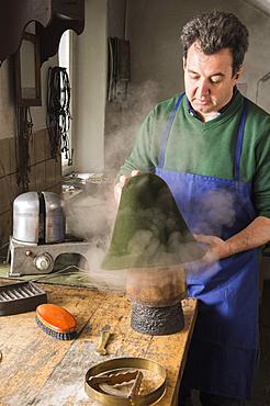 Man fitting wet hat body to wooden form, hatmaker workshop, Bad Aussee, Styria, Austria, Europe