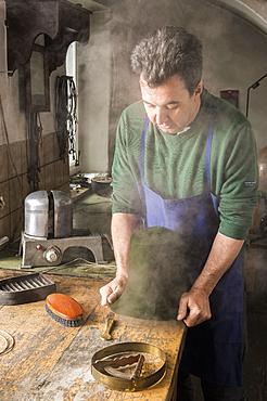 Man fitting wet hat body to wooden form, hatmaker workshop, Bad Aussee, Styria, Austria, Europe