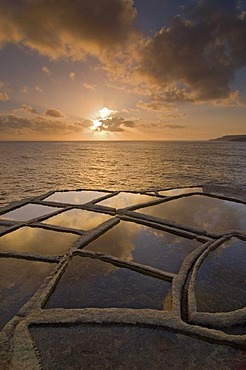 Sunrise and clouds above the typical salt pans or salterns, Qbajjar, near Marsalforn, northern coast of Gozo, Malta, Europe