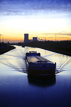 Cargo ship at dawn, Datteln-Hamm-Kanal, canal, near Waltrop, Trianel coal-fired power plant on Stummhafen at back, North Rhine-Westphalia, Germany, Europe