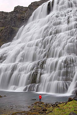 Woman standing in front of the Dynjandifoss or Fjallfoss waterfall, largest waterfall in the West Fjords, Northwest Iceland, Iceland, Europe