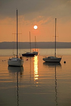 Boats on lake Ammersee against the setting sun, near Herrsching, Bavaria, Germany, Europe