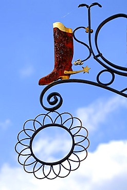 Riding boots with spurs, hanging sign of a shoe shop against a blue sky, Hauptstrasse, Gengenbach, Baden-Wuerttemberg, Germany, Europe