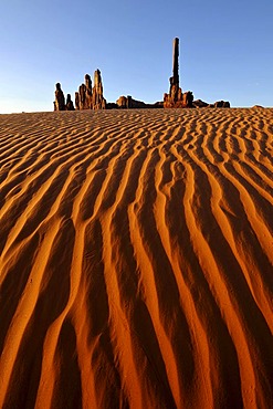 Sand dunes in front of Totem Pole and Yei Bi Chei rock formations after sunrise, Monument Valley, Navajo Tribal Park, Navajo National Reservation, Arizona, Utah, USA