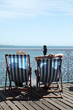 Couple relaxing in deckchairs, Brighton, Sussex, England, United Kingdom, Europe