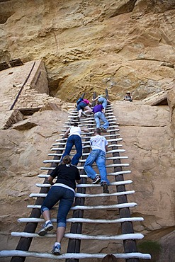 A park ranger watches as visitors climb a ladder to enter the Balcony House cliff dwelling at Mesa Verde National Park, featuring cliff dwellings of ancestral Puebloans that are nearly a thousand years old, Cortez, Colorado, USA