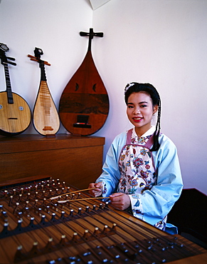 Woman dressed in traditional costume playing a zither, Beijing, China, Asia