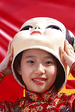 Young girl with Chinese Lucky God mask, Beijing, China, Asia