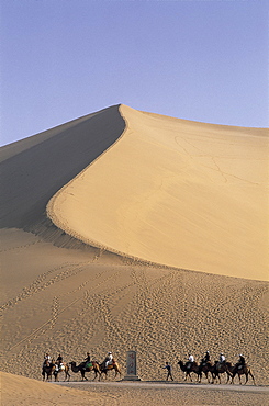 Tourists riding camels at Mount Mingshan, Dunhuang, Gansu Province, China, Asia