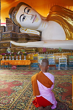 Nun in front of reclining Buddha statue, Shwethalyaung, Bago (Pegu), Myanmar (Burma), Asia