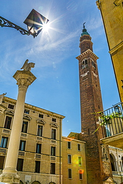 Sun peeking from street lamp and clock tower of Palladian Basilica in Piazza Signori, Vicenza, Veneto, Italy, Europe