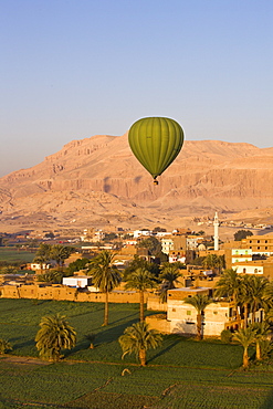 Hot air balloon suspended over the Theban necropolis and houses of Luxor, Thebes, Egypt, North Africa, Africa