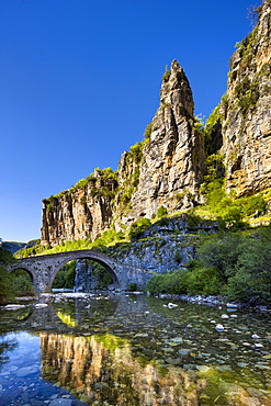 Towering cliffs and the 18th century Misius bridge over the Voidomatis River in the Vikos Gorge near Vitsa, Zagoria, Epirus, Greece, Europe