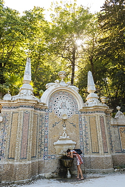 Woman using water fountain, Quinta da Regaleira, Sintra, Portugal, Europe