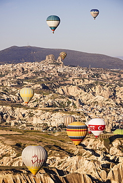 Hot air balloons flying among rock formations at sunrise in the Red Valley, Goreme National Park, UNESCO World Heritage Site, Cappadocia, Anatolia, Turkey, Asia Minor, Eurasia