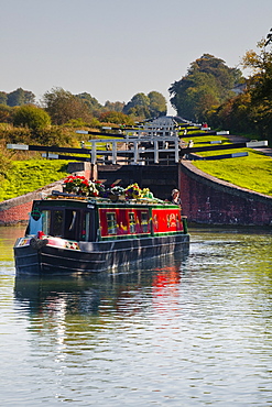 A canal boat leaving the famous series of locks at Caen Hill on the Kennet and Avon Canal, Wiltshire, England, United Kingdom, Europe