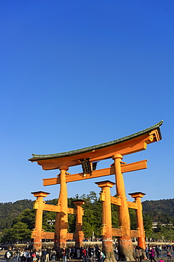 Tourists walking under the torii gate of Miyajima at low tide, Itsukushima, UNESCO World Heritage Site, Hiroshima Prefecture, Honshu, Japan, Asia