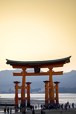 Tourists walking under the torii gate of Miyajima at low tide, Itsukushima, UNESCO World Heritage Site, Hiroshima Prefecture, Honshu, Japan, Asia