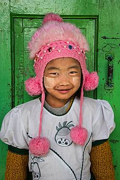 Burmese girl with her pompom cap, photographed in front of her classroom in the city of Nyuang U. On these cheeks, tanakha powder, to protect from the sun.