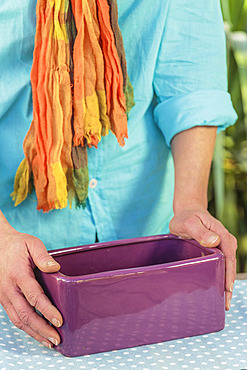 Step-by-step preparation of a forced narcissus planter. Woman holding an empty planter.