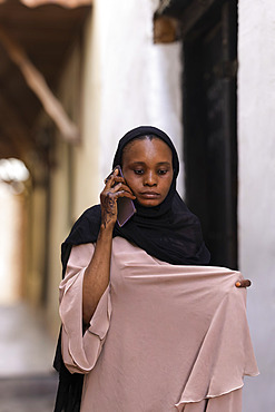 Traditional Muslim woman, abaya rolled up over her shoulders, Stone Town, in the capital of Zanzibar, Tanzania