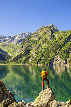 Hiker contemplating the Lac du Lauvitel (1530 m) on the GR 54 long-distance hiking trail, Tour de l'Oisans et des Ecrins, Veneon valley, Ecrins National Park, Isere, France