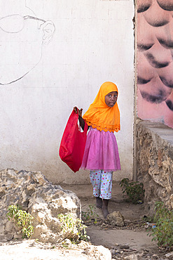 Colorful little girl returning from school, traditionally Muslim, she must wear the veil, Stone Town, capital of Zanzibar, Tanzania