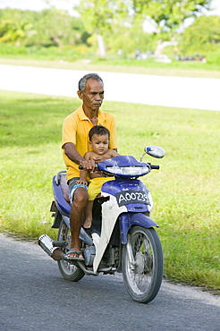 A Tuvaluan man and child on a motorbike on Funafuti  Atoll, Tuvalu, Pacific