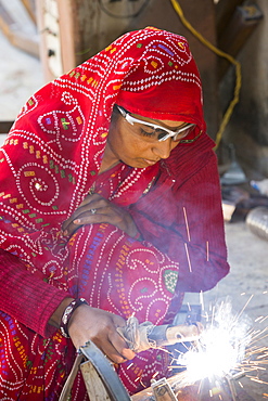 Women welding joints during the construction of solar cookers at the Barefoot College in Tilonia, Rajasthan, India. The Barefoot College is a worldwide charity, founded by Bunker Roy, its aims are, education, drinking water, electrification through solar power, skill development, health, women empowerment and the upliftment of rural people. Solar cookers save women having to walk to the froest to cut down wood for cooking, thus saving the forests, and a daily chore for woman.