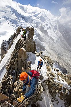 Mont Blanc from the Aiguille Du Midi above Chamonix, France, with climbers on the Cosmiques Arete, climbing the ladder to access the cable car station.