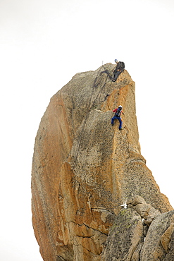 Climbers on a pinnalce on the Aiguille du Midi above Chamonix, France.