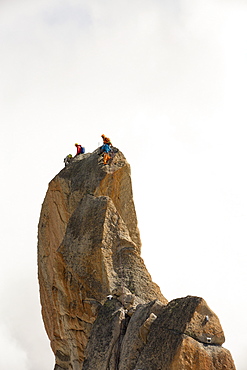 Climbers on a pinnalce on the Aiguille du Midi above Chamonix, France.